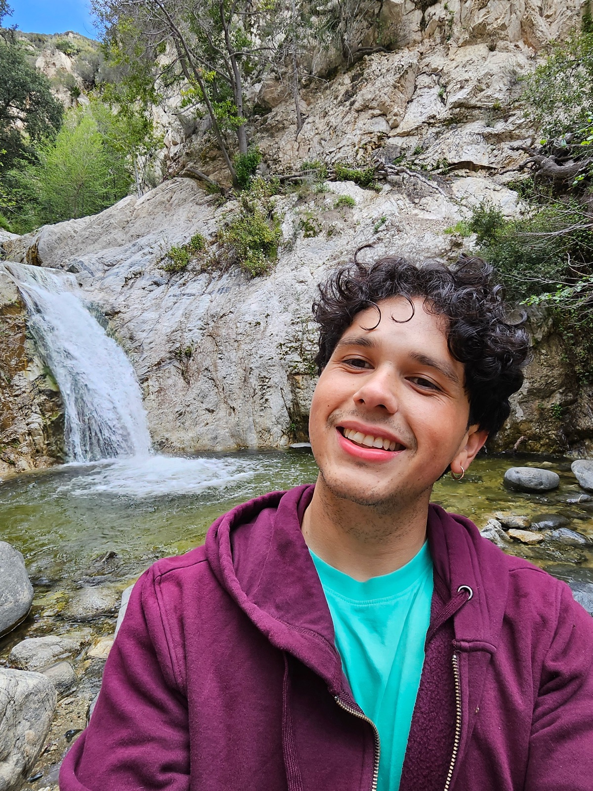 Kevin smiling beside a mountain waterfall